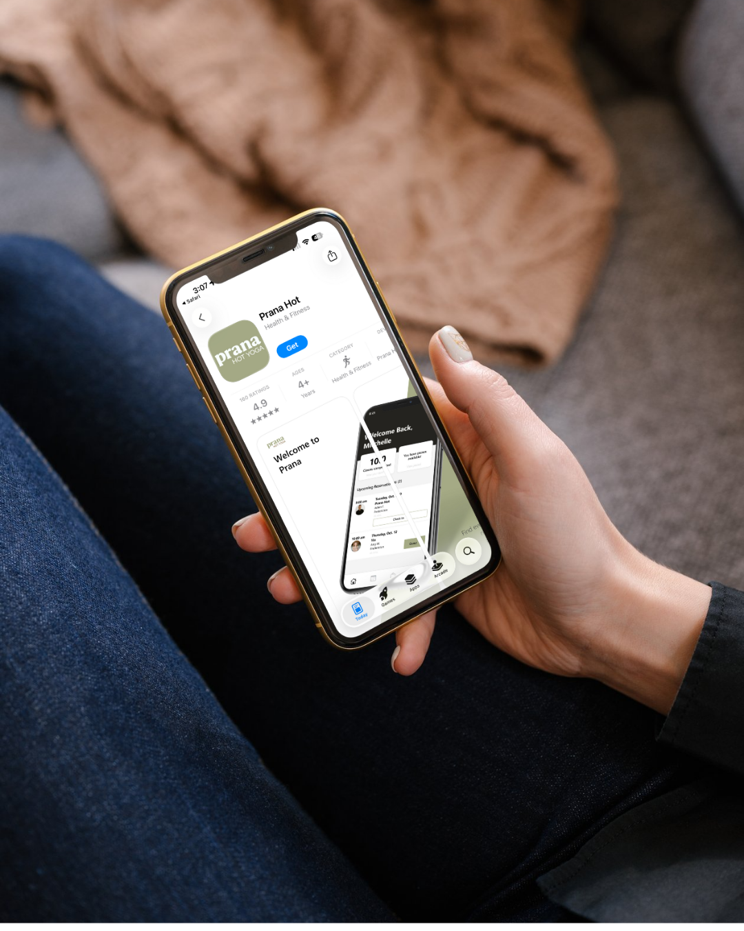Person holding a phone showing the Prana Hot app to book a first hot yoga class in Fredericton