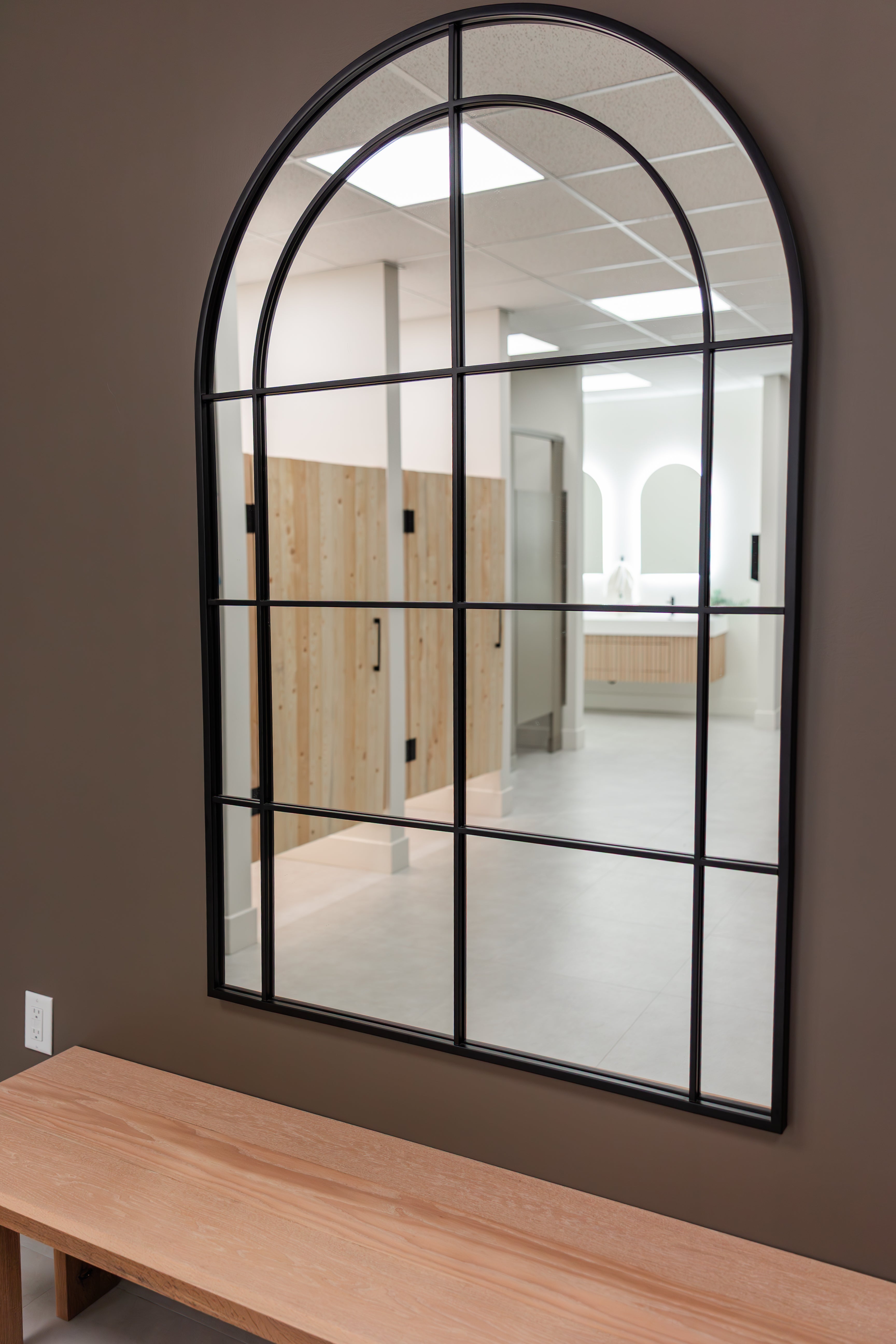 Arched wall mirror reflecting showers and double vanity in the Prana Fredericton changing room