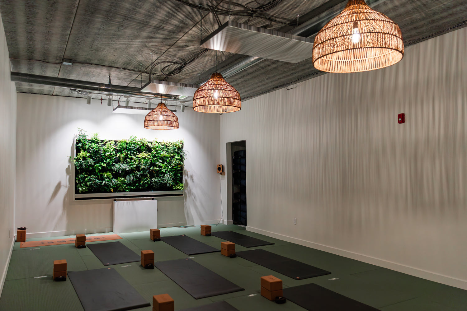 Moon Room at Prana Hot Yoga set up for unheated classes with yoga mats, cork blocks, living botanical wall, and ambient pendant lighting