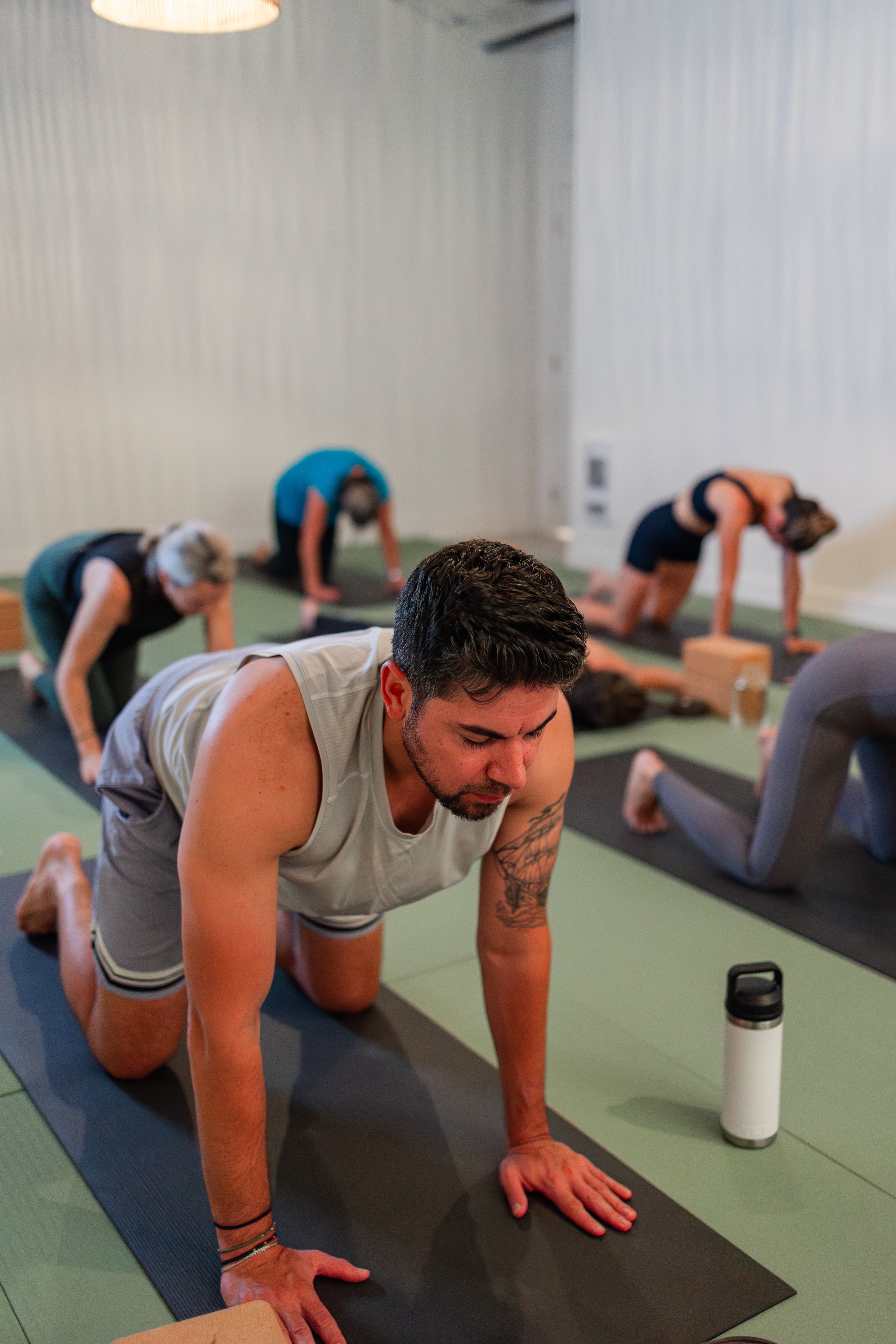 Private group yoga class at Prana Hot Yoga with participants of various fitness levels in plank pose, demonstrating customized sessions for corporate and celebration events in Fredericton